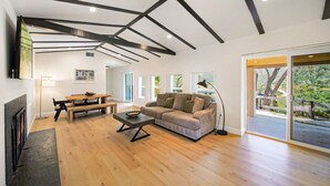 Ein modernes Wohnzimmer mit Kamin, Holzboden, einer Couch, einem Couchtisch und einem Esstisch.