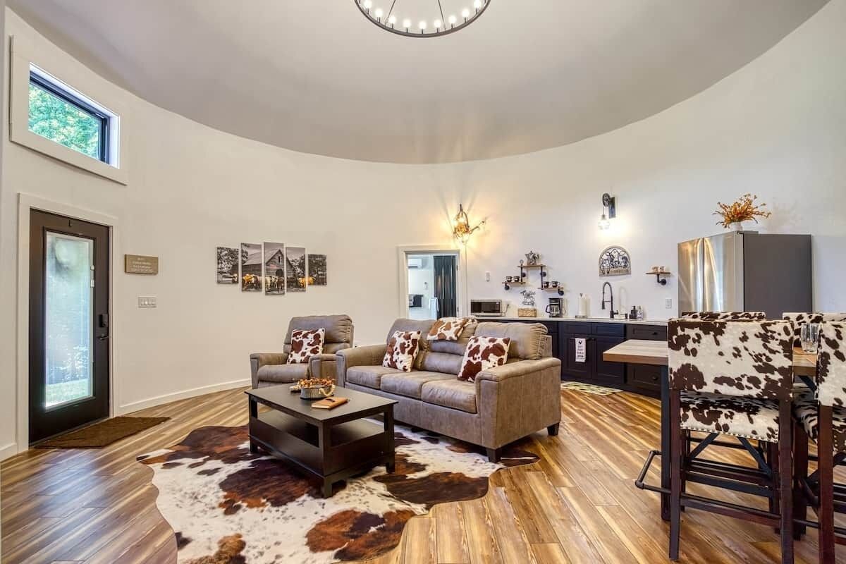A spacious living room with a large sofa, a coffee table, and a dining area with a cowhide rug.