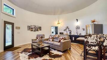 A spacious living room with a large sofa, a coffee table, and a dining area with a cowhide rug.