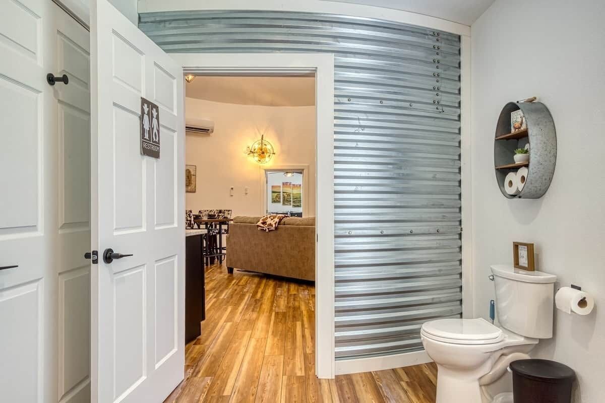 Een badkamer met een wit toilet, een prullenbak en een wandplank met toiletartikelen.