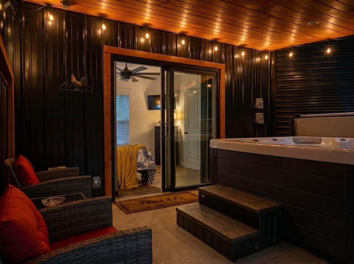 Een kamer met een bubbelbad, rieten meubels en een schuifdeur naar een badkamer.