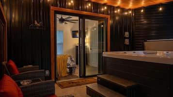 Een kamer met een bubbelbad, rieten meubels en een schuifdeur naar een badkamer.