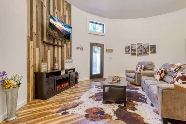 A living room with a fireplace, a sofa set, a cowhide rug, and a wooden wall panel.