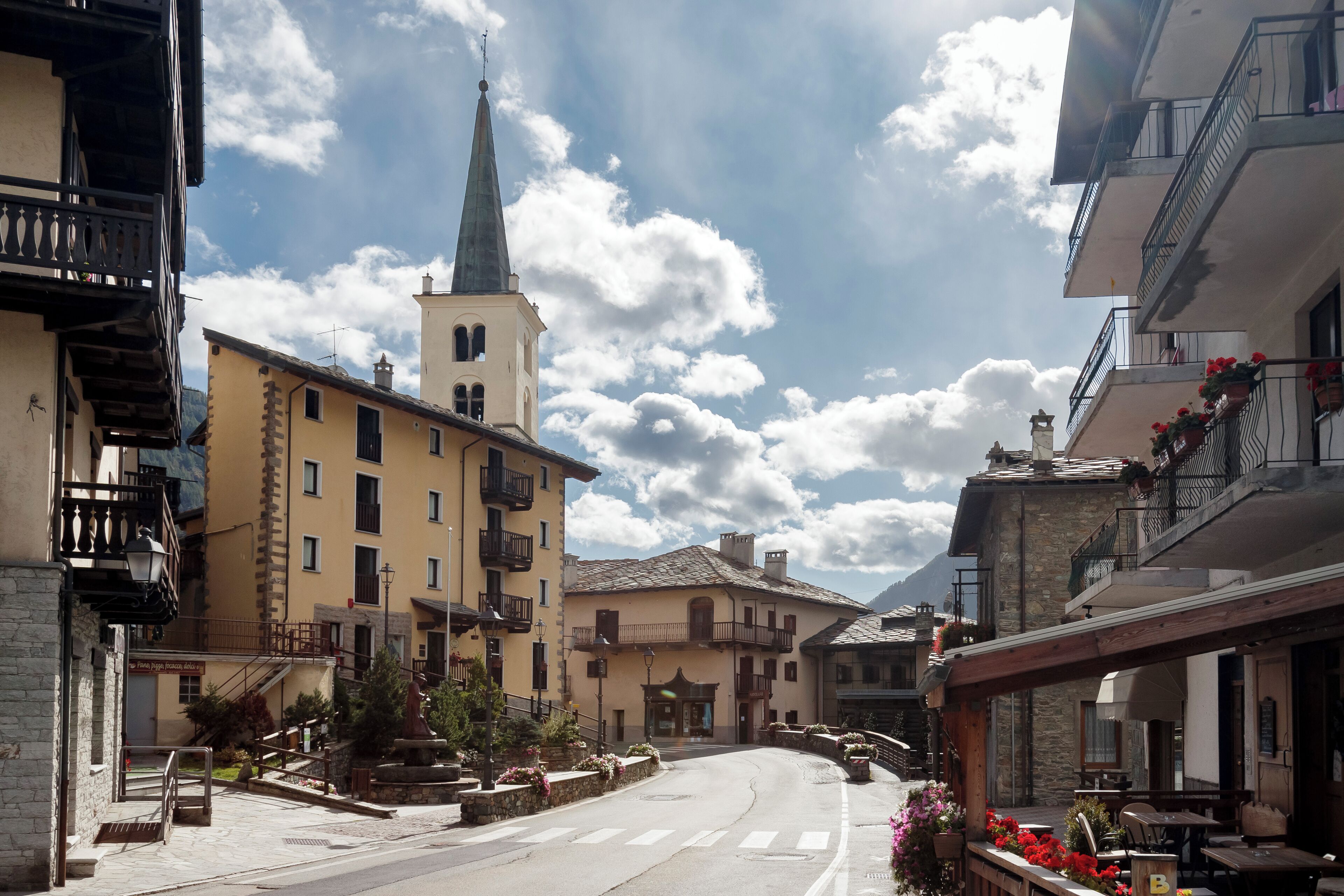 A street with buildings, a church, and outdoor seating.
