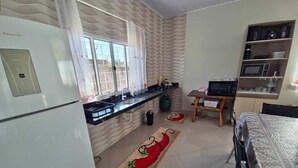 A compact kitchen with a refrigerator, stove, sink, and microwave. There is a dining area with a table and chairs.