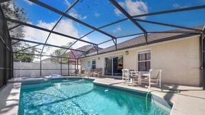 Ein Swimmingpool mit überdachter Terrasse, Liegestühlen und blauem Himmel.