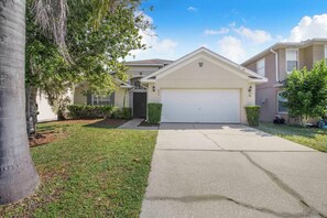 A residential house with a garage, a driveway, and a lawn. - Beautiful Family Villa, Heated Pool & Spa, Near Disney Parks (Kissimmee)