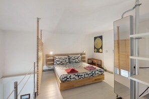 Ein Schlafzimmer mit einem hölzernen Bett, einem Nachttisch, einer Wandlampe und einem Fenster mit Jalousien.