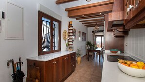 A kitchen with wooden cabinets, a marble countertop, and a bowl of fruit. - CH Villa Aström La Marquesa Golf (Ciudad Quesada)