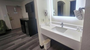 Ein Hotelbadezimmer mit einem großen Spiegel, zwei Waschbecken, einem Fön und einem Mülleimer.