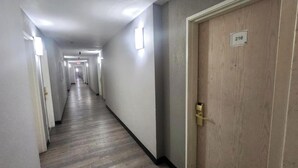 A corridor with doors on both sides, a wooden floor, and a number sign on the right door. - Sunport Suites near Albuquerque Airport I 25 (Albuquerque)