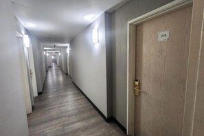A corridor with doors on both sides, a wooden floor, and a number sign on the right door.
