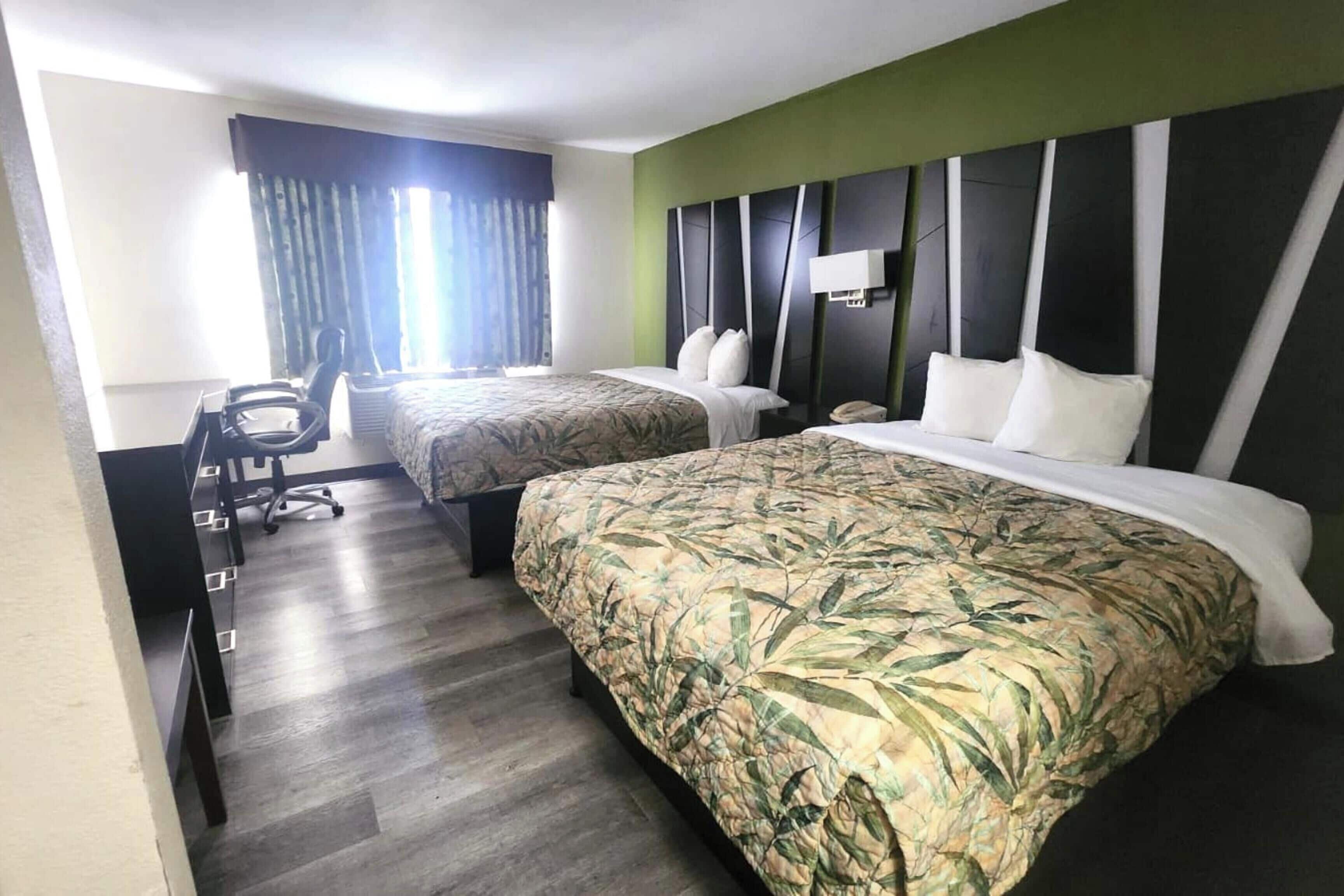 Une chambre d’hôtel avec deux lits, un bureau et une chaise.