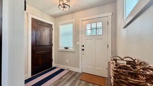 A hallway with a wooden door, a white door with a window, a striped rug, and a woven basket. - Dawson Cottage Dog friendly, close to town (McCall)
