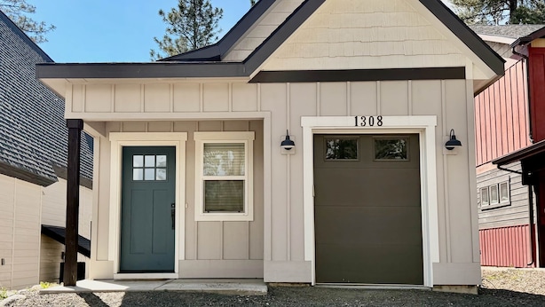 A single-story building with a beige exterior, a dark green front door, and a garage with the number 1308. - Dawson Cottage Dog friendly, close to town (McCall)