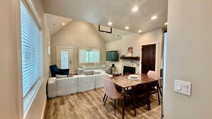 A living room with a sofa, a dining table with chairs, a fireplace, and a TV mounted on the wall. - Dawson Cottage Dog friendly, close to town (McCall)
