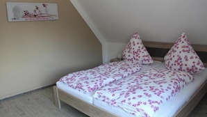 Ein Einzelbett mit floralem Bettbezug in einem Zimmer mit geneigter Decke.