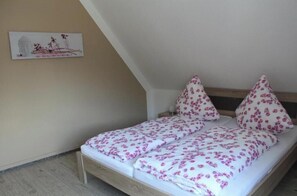 Ein Einzelbett mit floralem Bettbezug in einem Zimmer mit geneigter Decke.