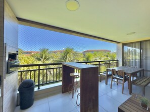 Ein Balkon mit Tisch, Stühlen, einer Mülltonne und einem Grill.