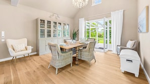 Un espace repas comprenant une table, des chaises, un buffet et un lustre.