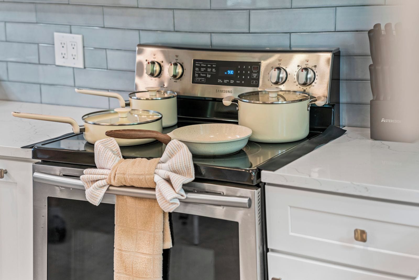 A kitchen with a stainless steel stove, pots, and a towel hanging on the oven door.