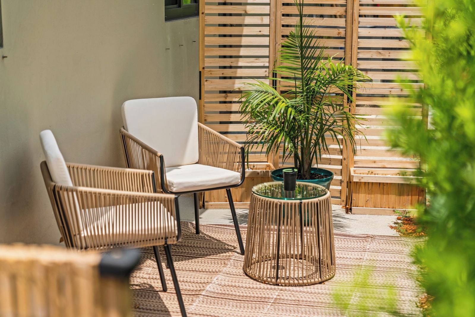 A patio area with wicker chairs, a round table, and a potted plant.