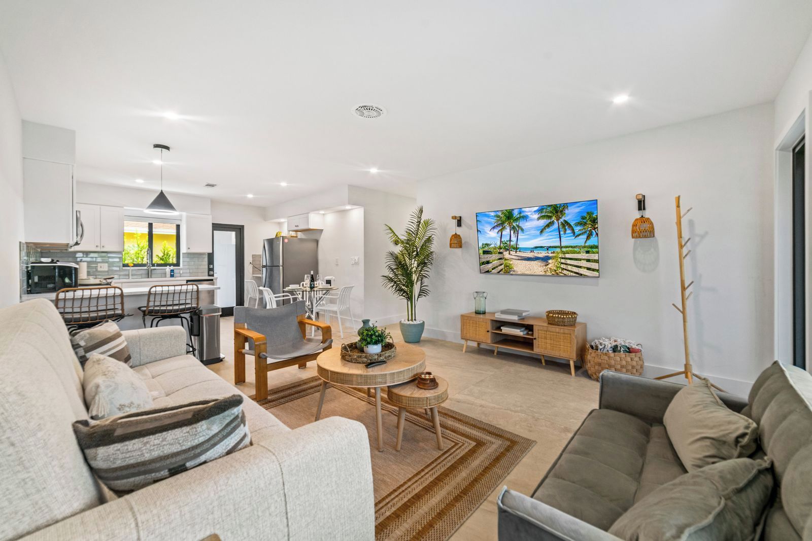 A modern living room with a sofa, a dining table, and a kitchen in the background.