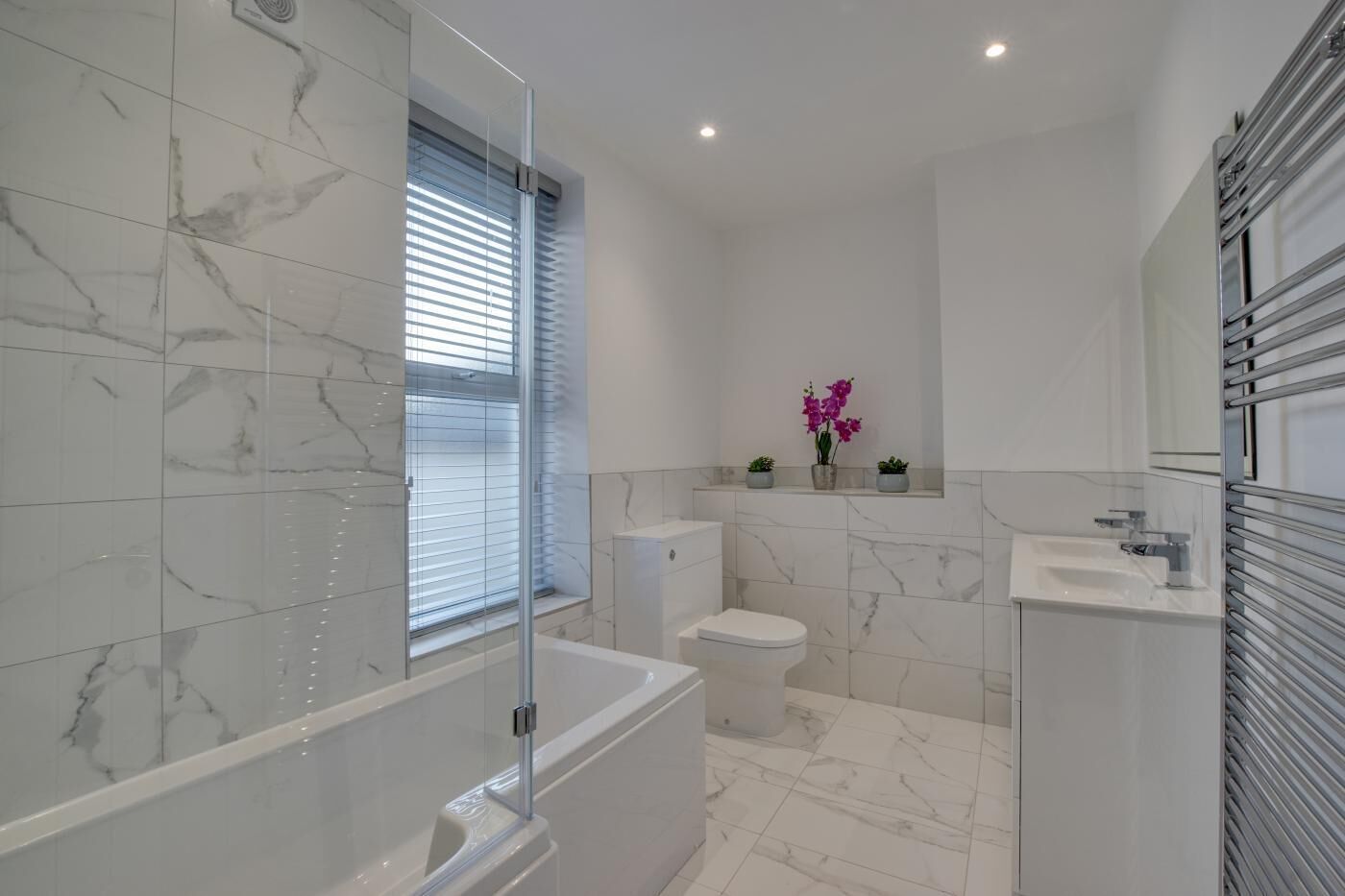 Une salle de bain moderne avec une douche à parois de verre, des toilettes, un lavabo et un meuble-lavabo avec un miroir.