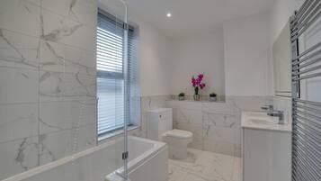 Une salle de bain moderne avec une douche à parois de verre, des toilettes, un lavabo et un meuble-lavabo avec un miroir.