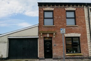A two-story brick building with a black garage door and a single entrance door.