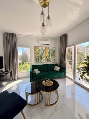 Ein modernes Wohnzimmer mit einem grünen Sofa, einem schwarzen Couchtisch und einem Fernseher auf einem Schrank.
