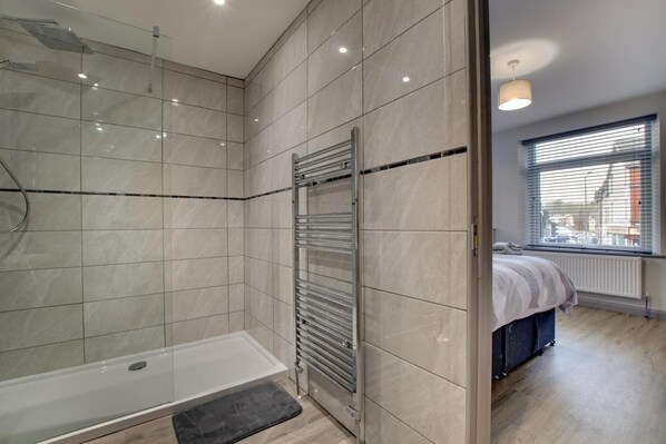 A modern bathroom with a glass shower enclosure, a walk-in shower, and a built-in towel rack.