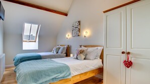 Un dormitorio con dos camas, una ventana, un armario y una lámpara fijada a la pared.
