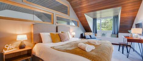 A bedroom with a large bed, bedside lamps, a desk, and a window with curtains.