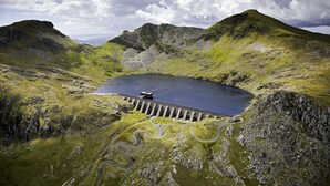 Un paysage montagneux avec un barrage et une route sinueuse.