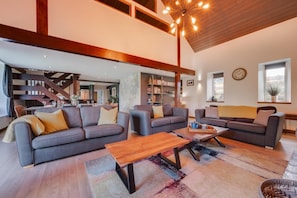 A spacious living area with a modern design, featuring sofas, a coffee table, and a staircase leading to an upper level. - 4 Bed in Ffestiniog (oc-bow172) (Ffestiniog)