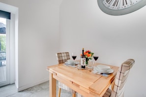 A dining table with chairs, a bottle of wine, glasses, and a flower arrangement. - 1 Bed in Aberystwyth (oc-bow182) (Rhos-y-garth)