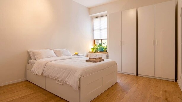 Un dormitorio con cama, ventana, radiador y armario.