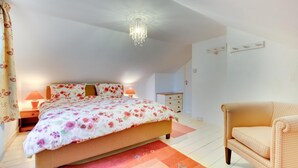 Une chambre à coucher avec un lit, des lampes de chevet, une chaise, une commode et un lustre.