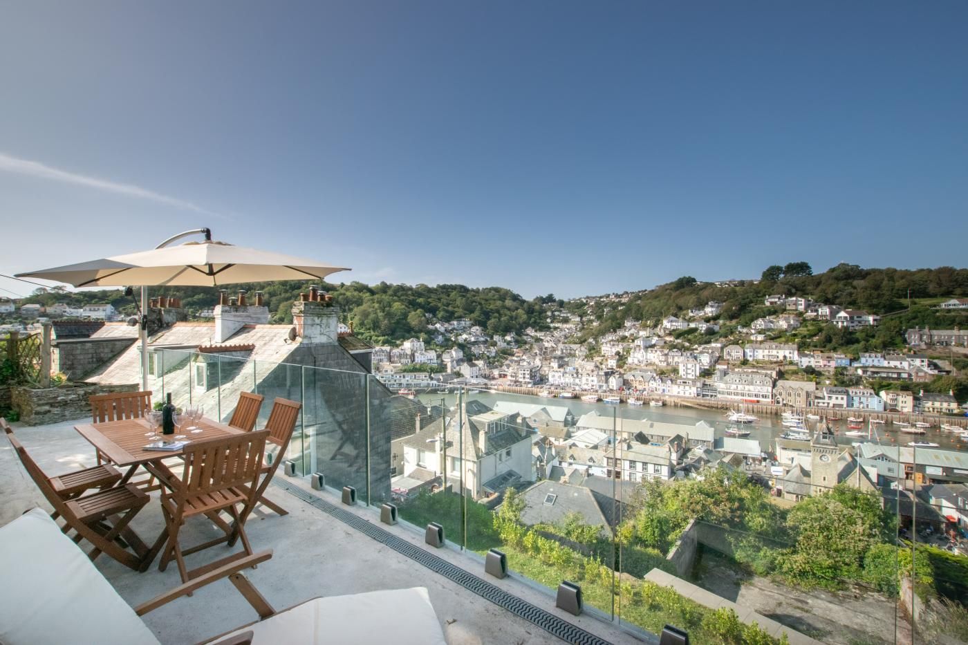 Une terrasse avec une table et des chaises, d’où l’on a vue sur une ville avec ses bâtiments et une rivière.