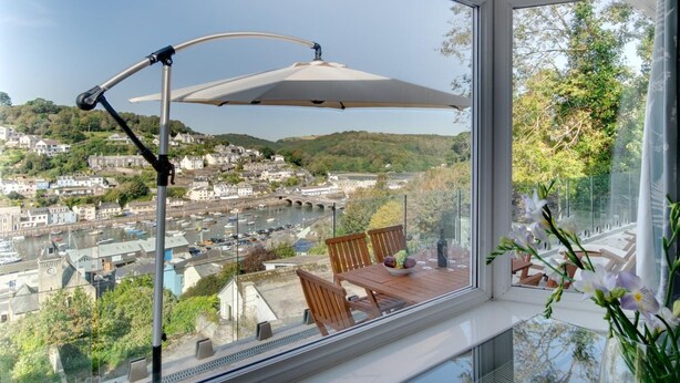 Un balcon avec une table, des chaises et une vue sur la ville et la rivière.