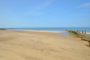A beach with a wooden walkway leading to the water, a sandy shore, and a clear sky. - 3 Bed in Walcott (oc-2135) (Walcott)