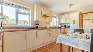 Een keuken met witte kastjes, een betegelde vloer en een eettafel gedekt met ontbijtspullen.