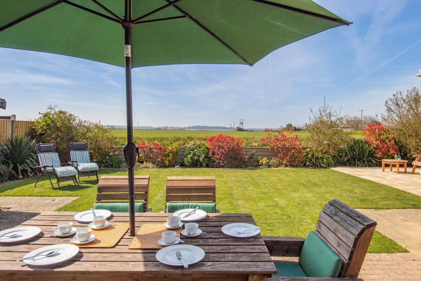 Eine Terrasse im Freien mit Esstisch, Stühlen und Sonnenschirm.