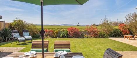 Eine Terrasse im Freien mit Esstisch, Stühlen und Sonnenschirm.