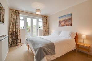 A bedroom with a bed, a chair, a nightstand, and a painting on the wall. - 1 Bed in Burnham Market (oc-2193) (Burnham Market)