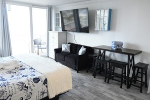 Een hotelkamer met een bed, een slaapbank, een televisie, een bureau met krukken, en een raam met gordijnen.