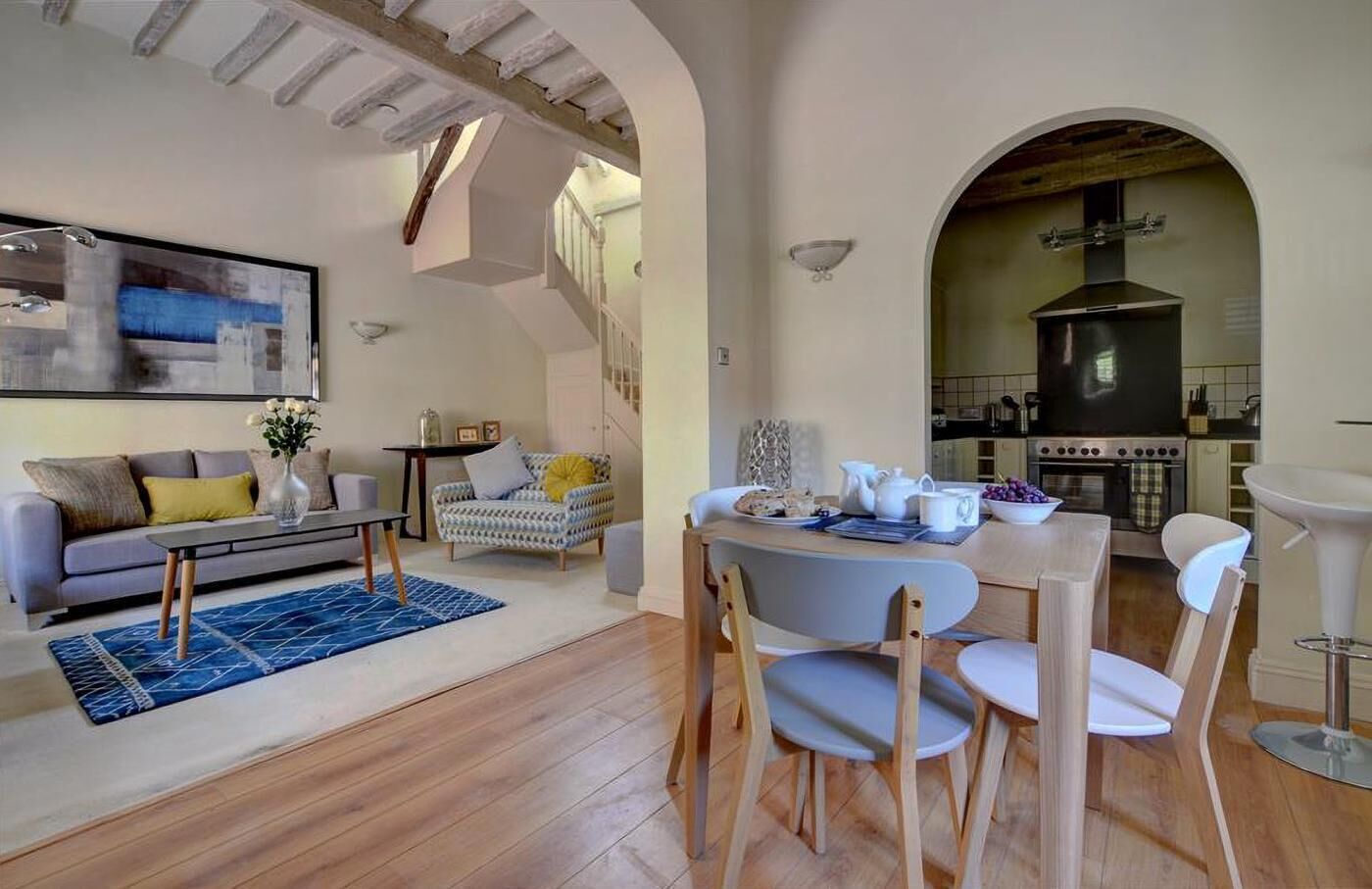 A modern living room with a sofa, coffee table, and a dining area with chairs and a table set for breakfast.