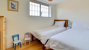 A bedroom with two beds, a window, a chair, and a wardrobe. - 2 Bed in Swanage (oc-wy412) (Swanage)