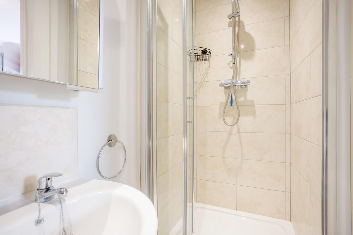 Une salle de bain moderne avec une douche à parois de verre, une baignoire blanche et un lavabo agrémenté d’un porte-serviettes.